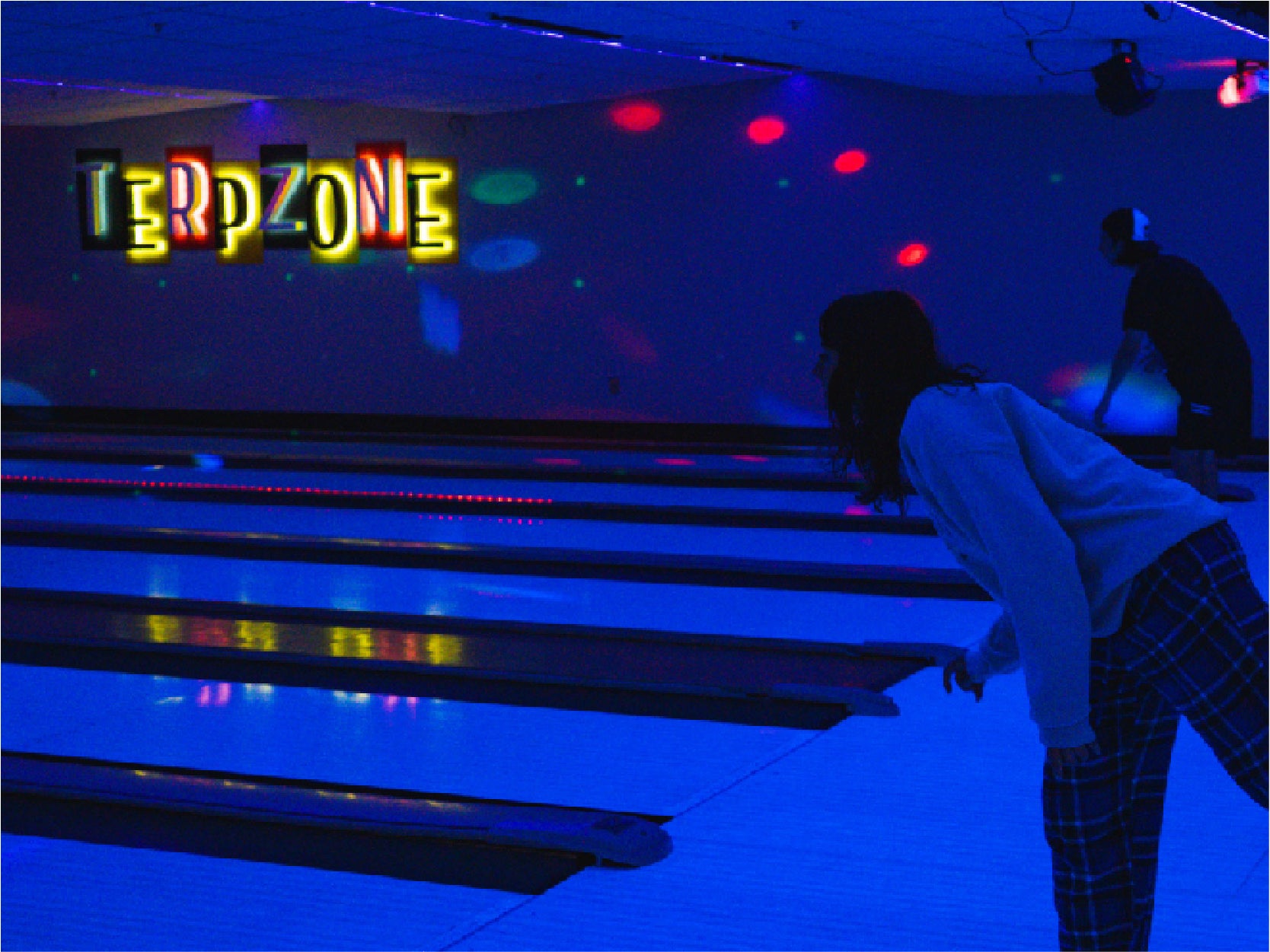 A UMD student bowls under black lights in the TerpZone