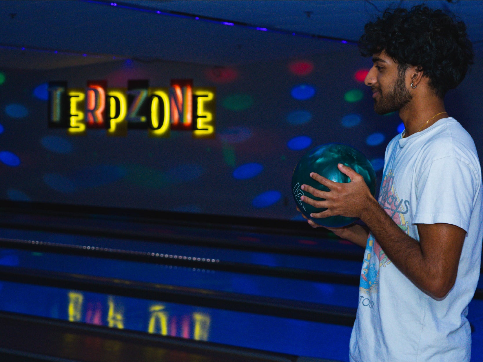 A University of Maryland student holds a bowling ball under black lights in the TerpZone
