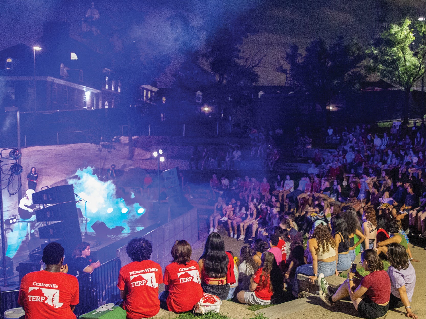 A large group of University of Maryland students watch a late-night concert at the Nyumburu Amphitheater