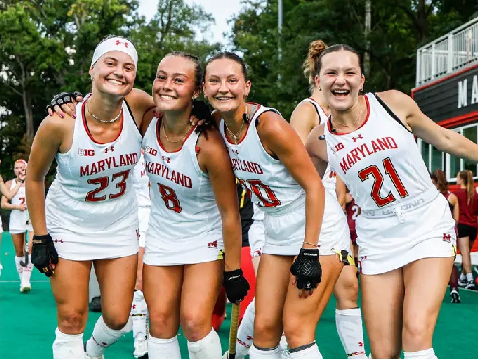 Members of Maryland's field hockey team pose and smile on the field