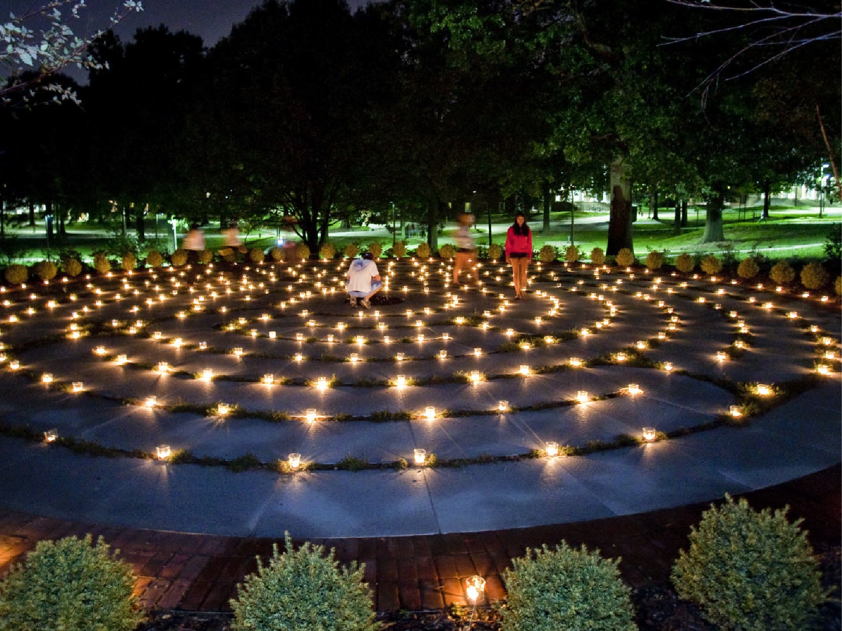 Several people walking the University of Maryland Memorial Chapel's labyrinth at night, illuminated by many small candles