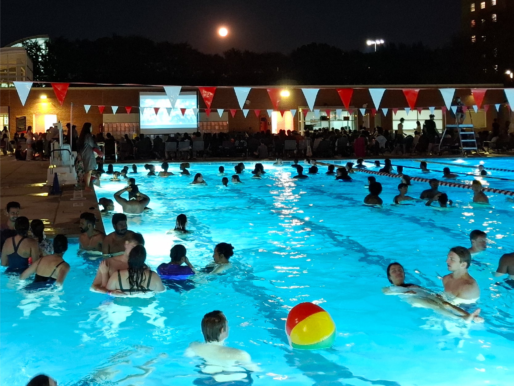 UMD students watch a movie while swimming in the pool at night