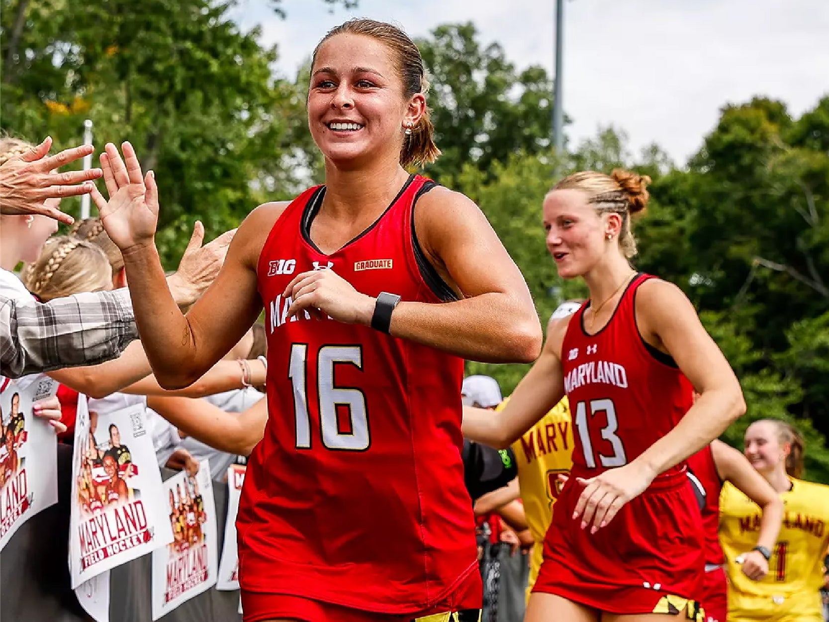 Members of UMD's field hockey team high five fans.