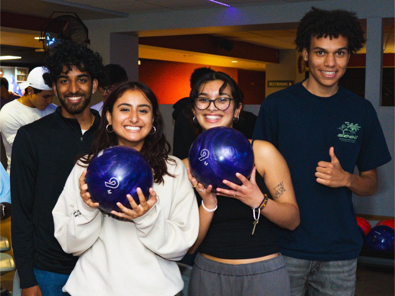 Photo of three students in TerpZone posing with bowling balls.