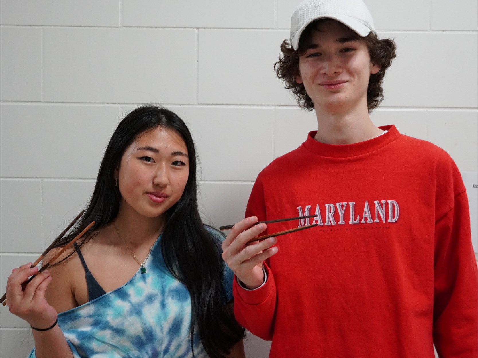 A photo of two students holding chopsticks that they crafted in the Keystone Woodshop
