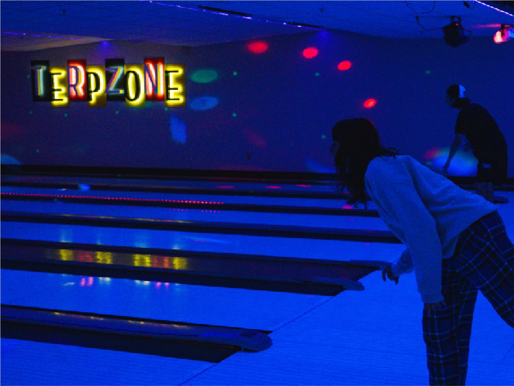 A photo of a student bowling in the TerpZone during a Glow Bowling event.