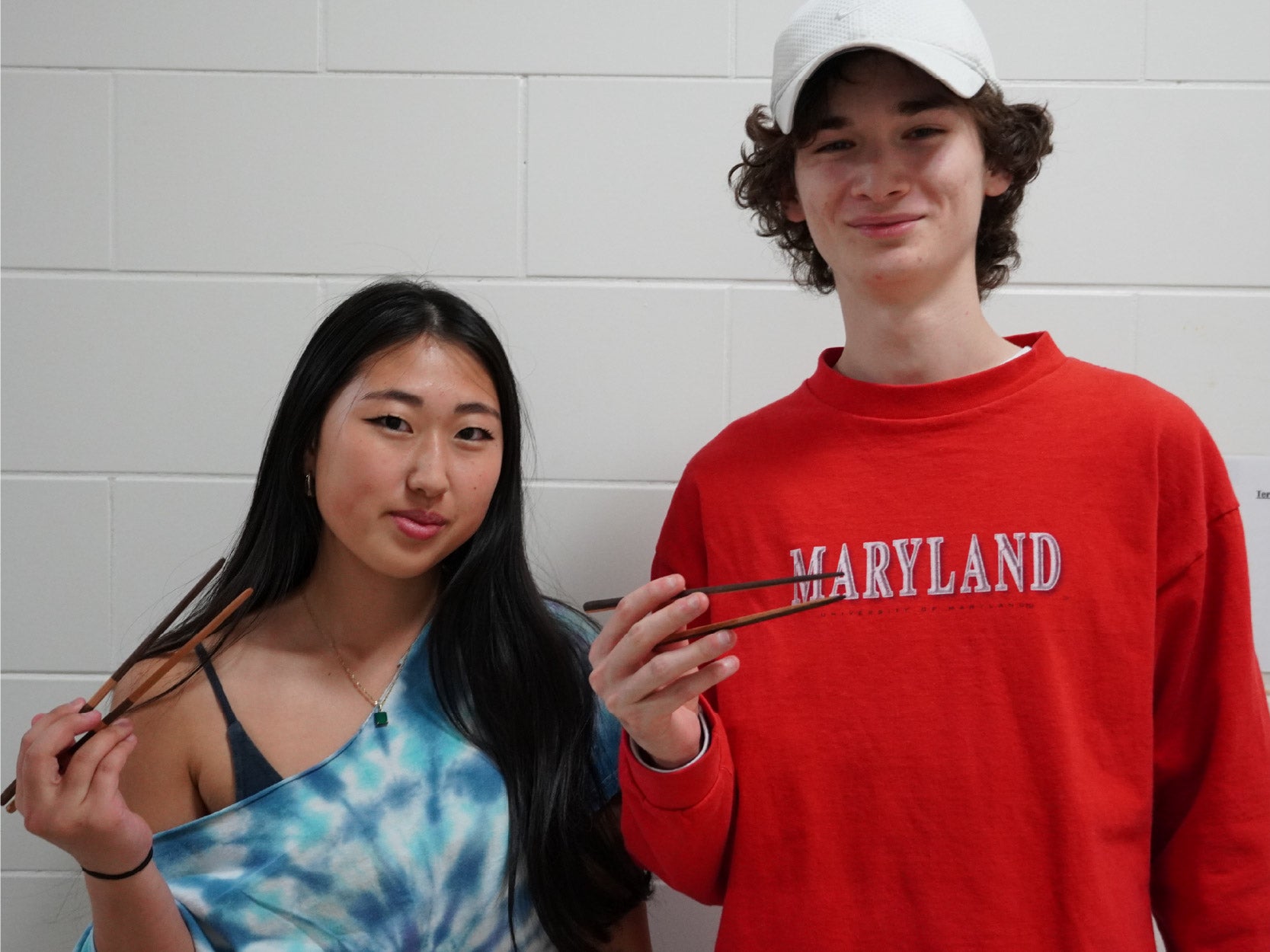 A photo of two students holding chopstick projects made in the Keystone woodshop.