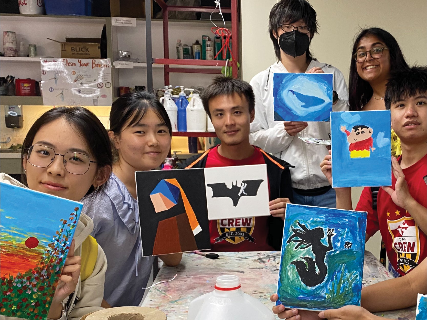 A photo of 5 students holding up paintings that they made in Studio A.