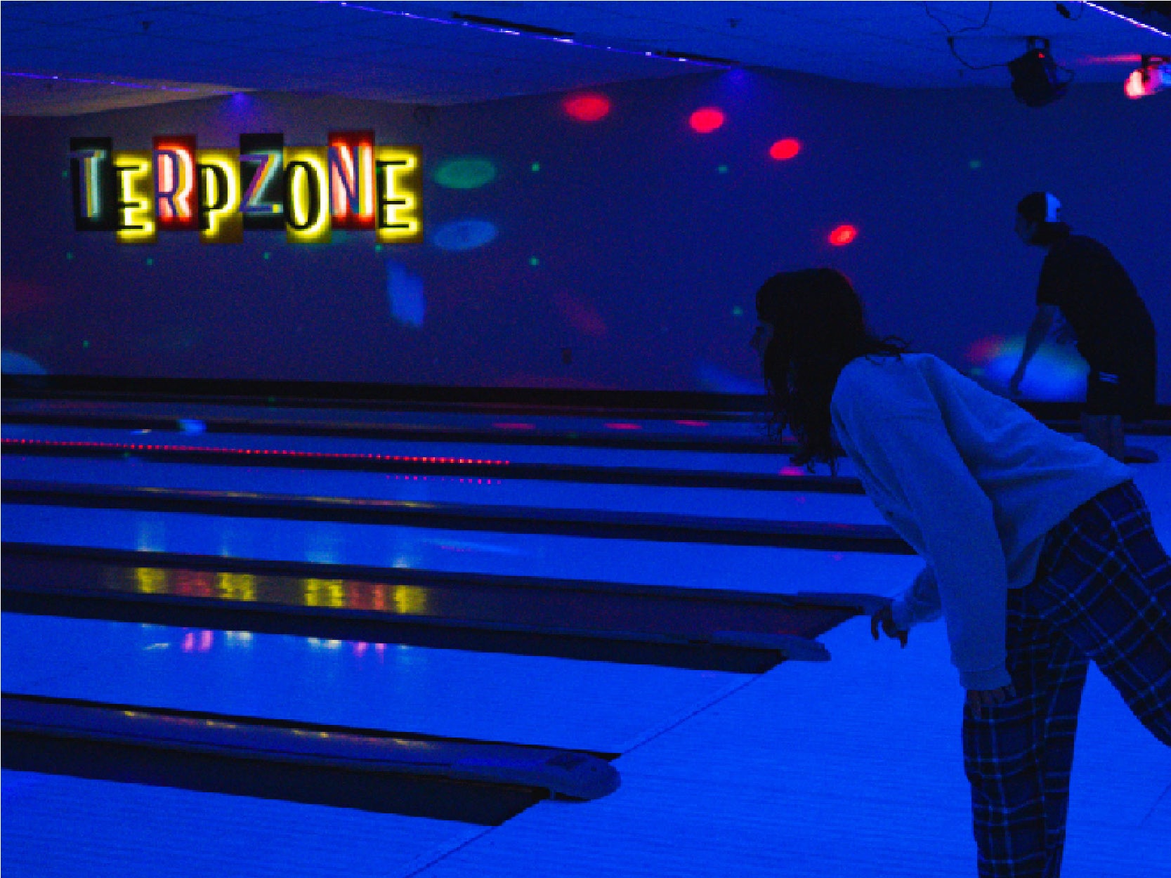 A photo of two students bowling in TerpZone during a Glow Bowling night.